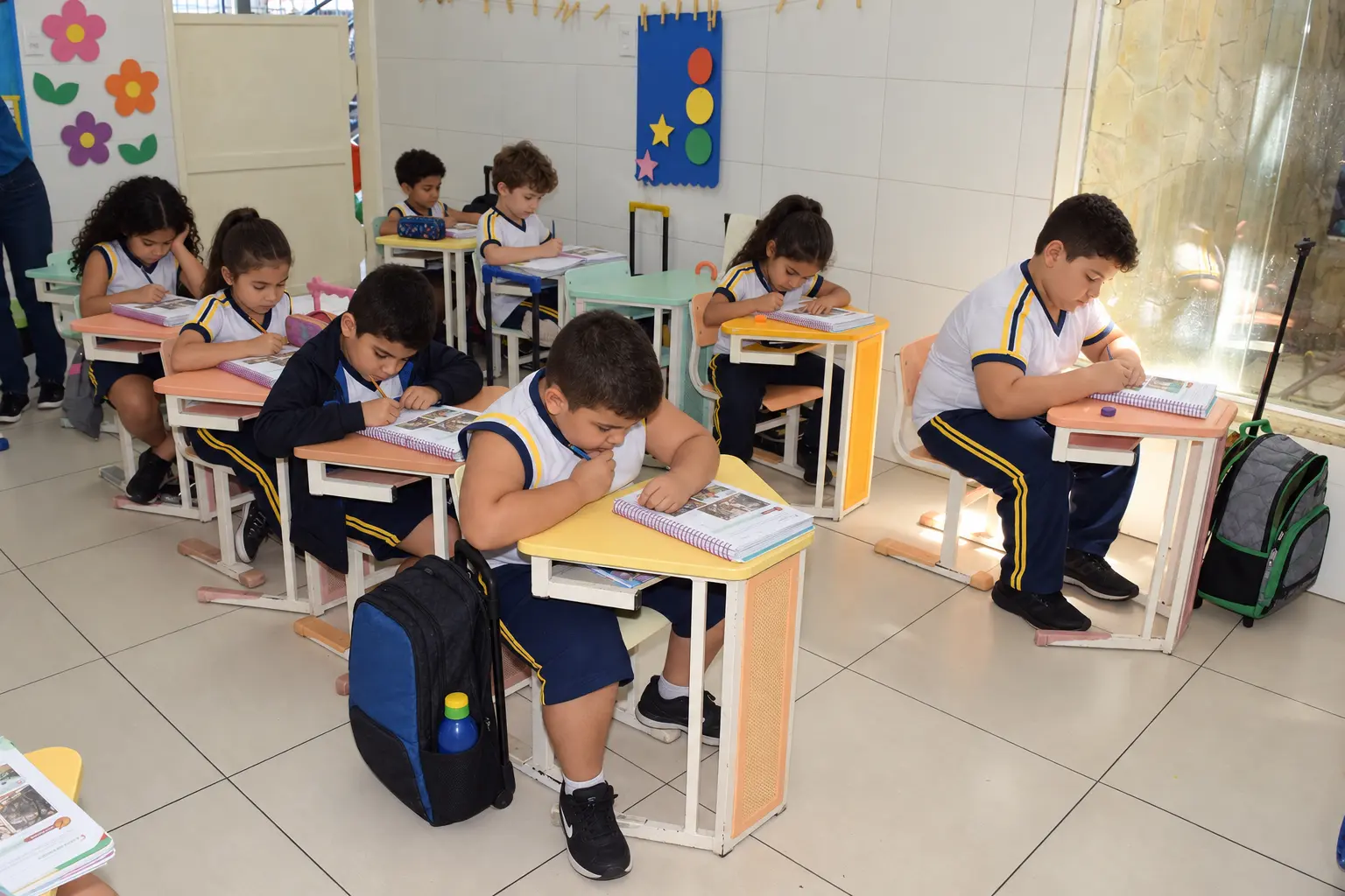 Alunos dos anos iniciais do Millennium fazendo atividade nas carteiras coloridas